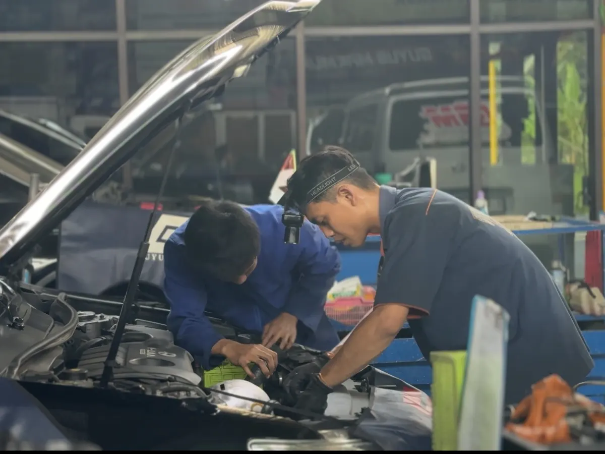 Mekanik Guyub Makmur Gemilang memeriksa ruang mesin mobil pelanggan